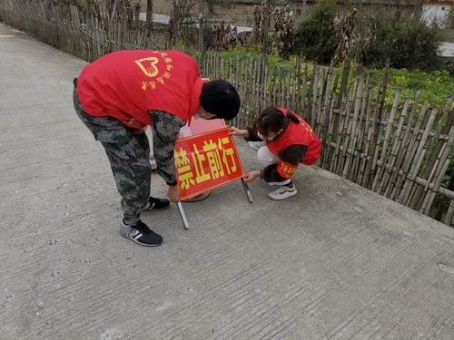 图为青年志愿者们在疫情防控检查站张贴“禁止前行”等资料.jpg